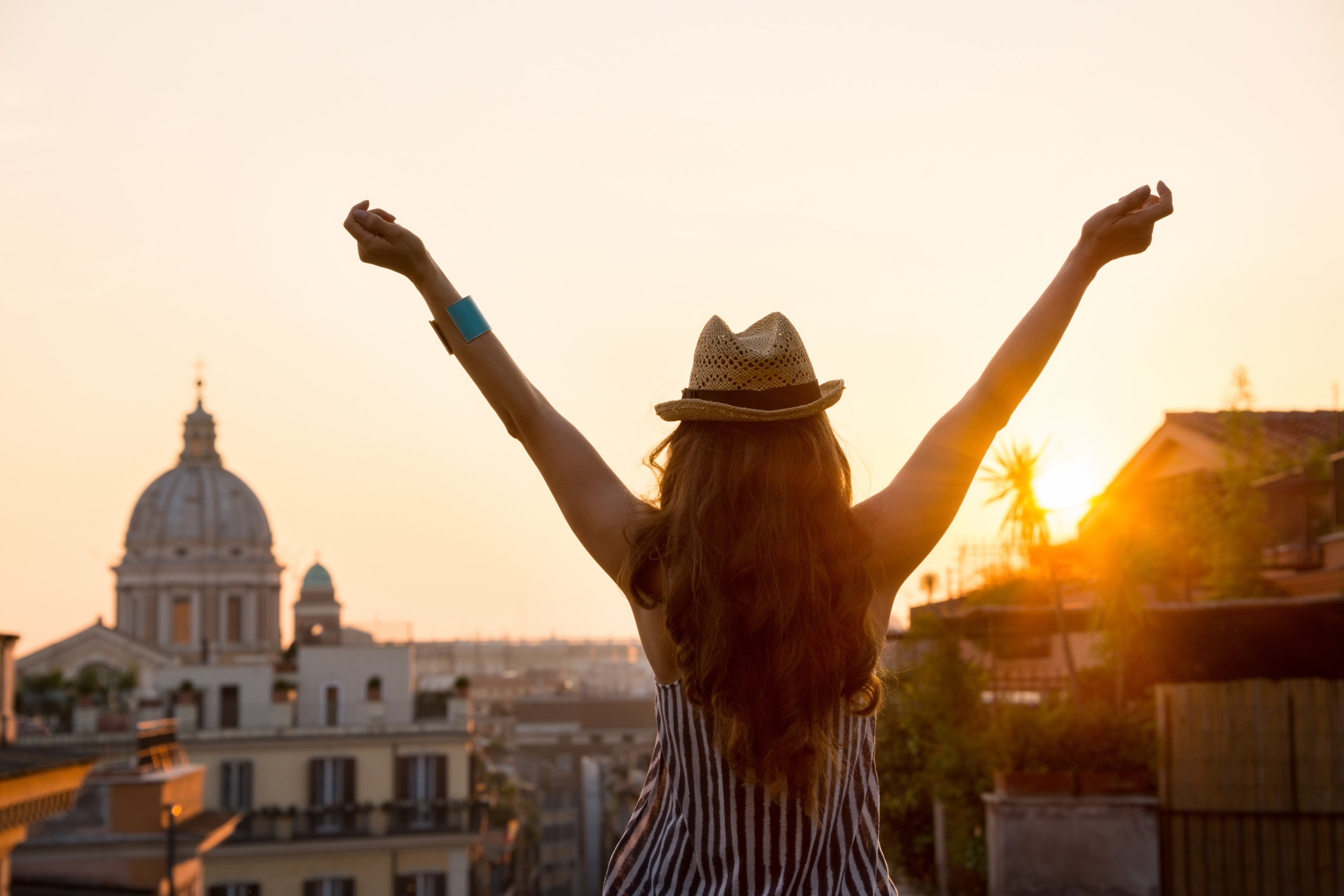 Woman from behind with outstretched arms in Rome at sunset retirement